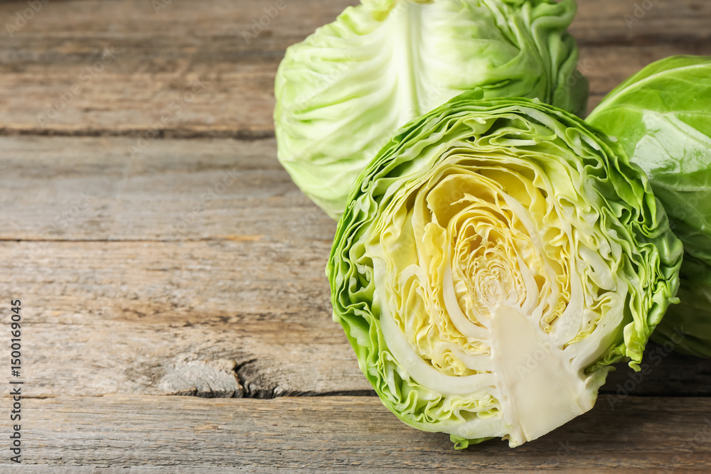 Fototapeta premium Fresh whole and cut cabbages on wooden table, closeup. Space for text