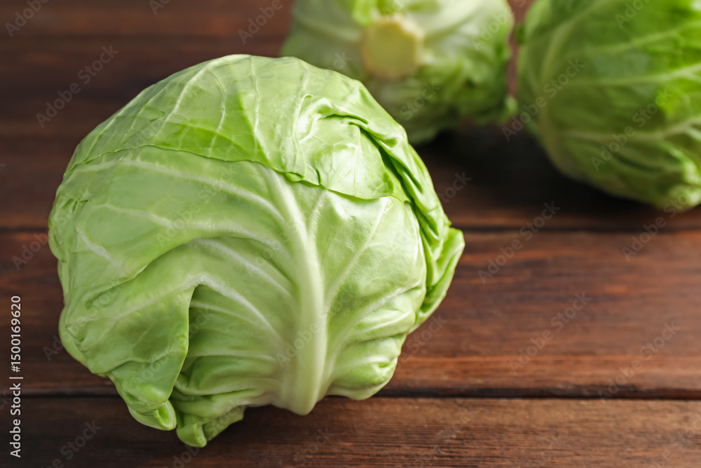 Fototapeta premium Fresh whole cabbages on wooden table, closeup. Space for text