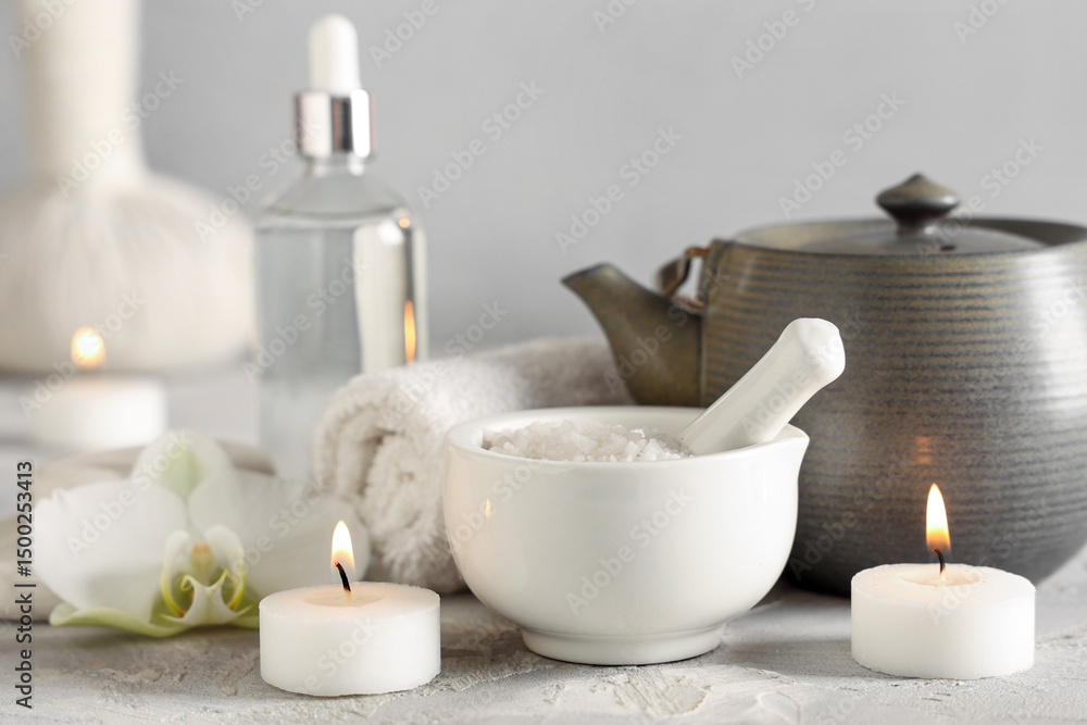 Composition with spa accessories, cosmetics, teapot and burning candles on light table Composition with spa accessories, cosmetics, teapot and burning candles on light table