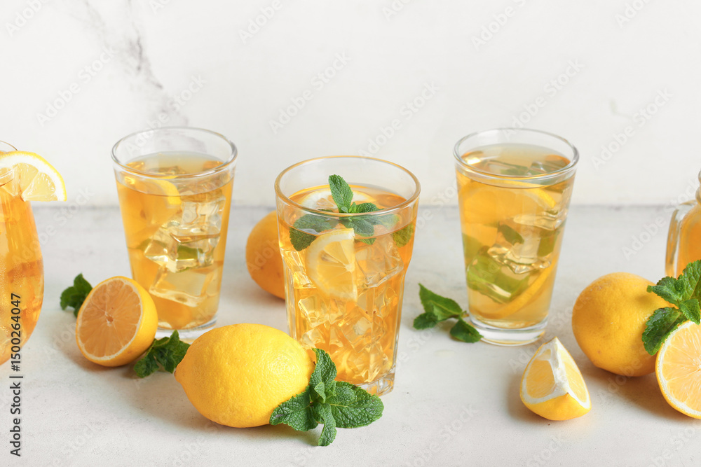 Fototapeta premium Glasses of lemon ice tea with mint and citrus fruits on white background