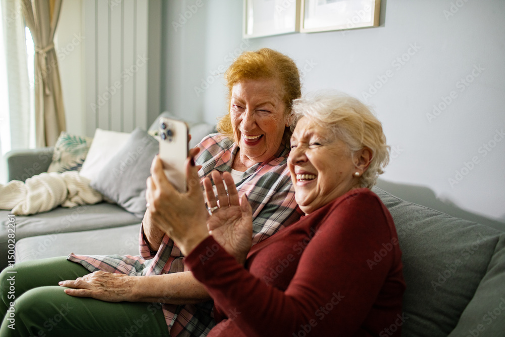 Senior lesbian couple laughing while video chatting with family on smartphone at home Senior lesbian couple laughing while video chatting with family on smartphone at home