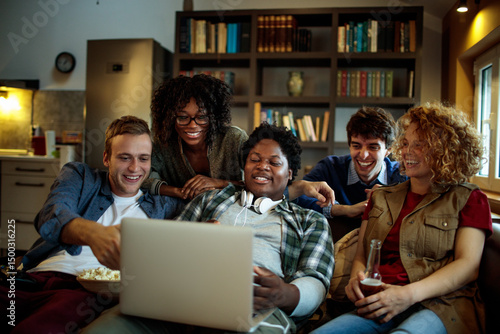 Young and diverse group of friends watching a movie on laptop in the living room on the couch