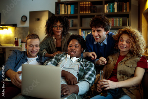 Young and diverse group of friends watching a movie on laptop in the living room on the couch