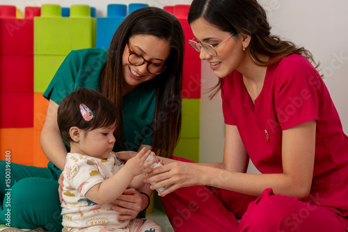 Pediatricians assisting baby girl in play therapy session