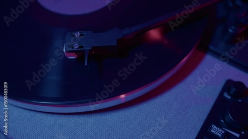 Top view footage, an artistic approach to a vinyl record player is showcased, illuminated with ambient lighting that enhances the mood of music and creativity in a modern setting.