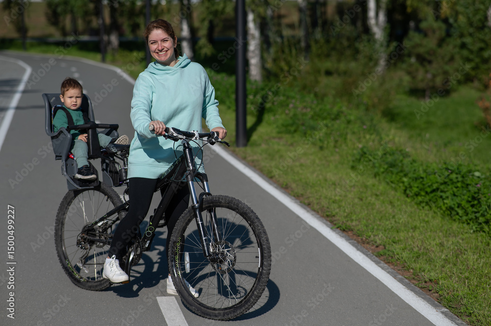 Caucasian woman riding a bicycle with her toddler son sitting behind her in a child seat. Caucasian woman riding a bicycle with her toddler son sitting behind her in a child seat.