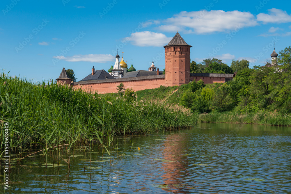 View of the Spaso-Evfimiev Monastery (a monastery of the Vladimir Diocese of the Russian Orthodox Church) on the bank of the Kamenka River on a sunny summer day, Suzdal, Vladimir region, Russia View of the Spaso-Evfimiev Monastery (a monastery of the Vladimir Diocese of the Russian Orthodox Church) on the bank of the Kamenka River on a sunny summer day, Suzdal, Vladimir region, Russia