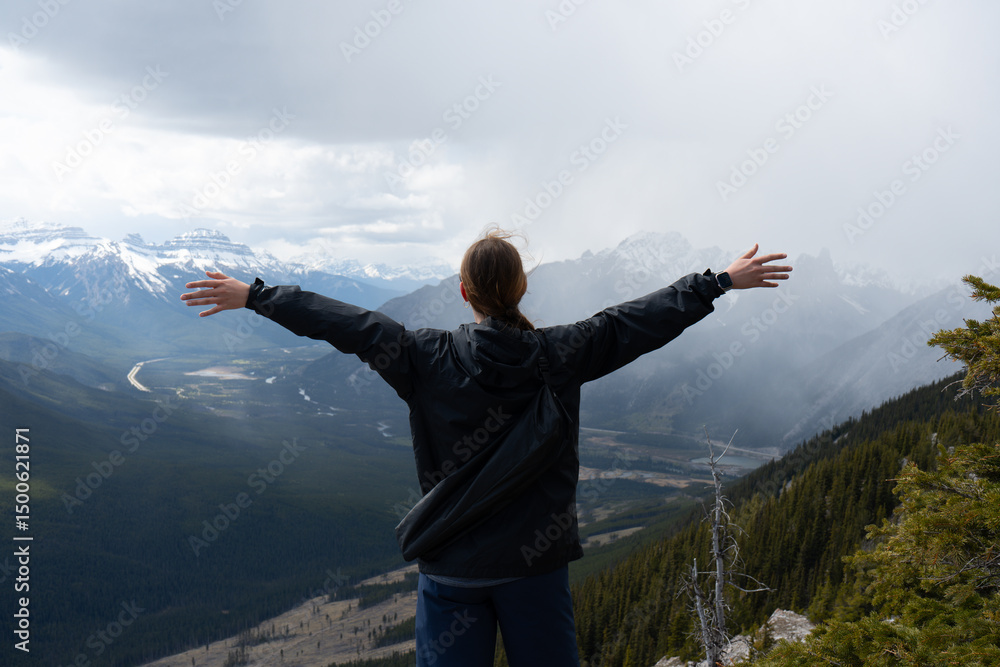 Girl with arms outstretched, looking at snowy peaks Girl with arms outstretched, looking at snowy peaks