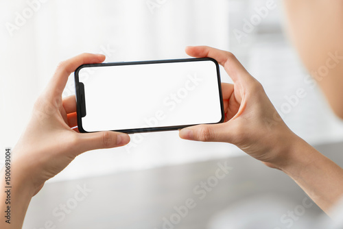 Hand holding smartphone with a blank screen on table, for putting advertising to promote.
