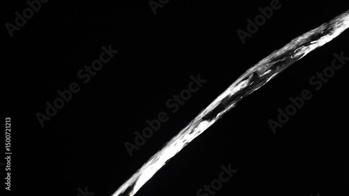Crystal clear stream of water flowing on isolated black background, close up, slow motion. Transparent pouring stream of clean water cascading against a dark backdrop. Concept of drinking pure water