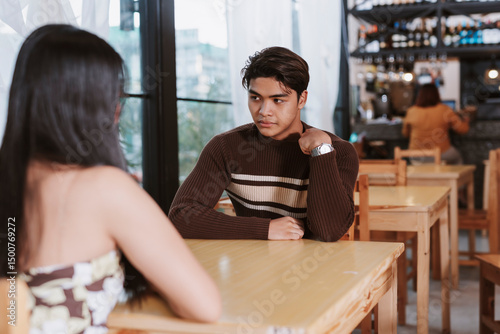 Quadro su tela A Gen Z Southeast Asian man awkwardly adjusts his shirt during a first date that lacks chemistry or mutual interest