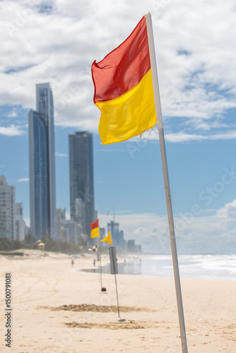 Obraz na plátně Red and yellow safety flags waving on sunny day on beach Gold Coast
