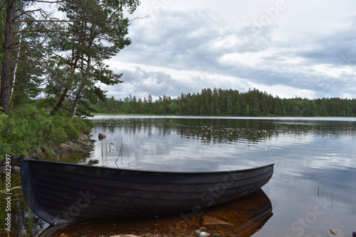 Kleines braunes Ruderboot liegt am Ufer eines ruhigen Sees in Schweden bei Gislaved