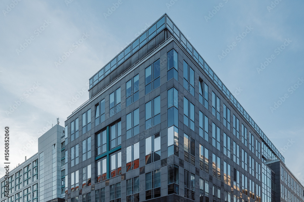A sleek, modern office building with a glass and steel facade stands prominently against a soft blue evening sky. A sleek, modern office building with a glass and steel facade stands prominently against a soft blue evening sky.