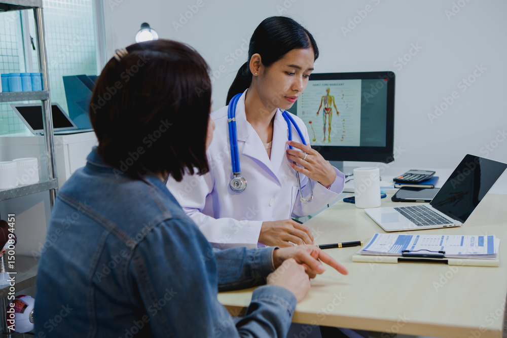Fototapeta premium An Asian female specialist attentively consults a patient, discussing symptoms and treatment options with care. She listens closely, offering professional medical advice and support in a calm