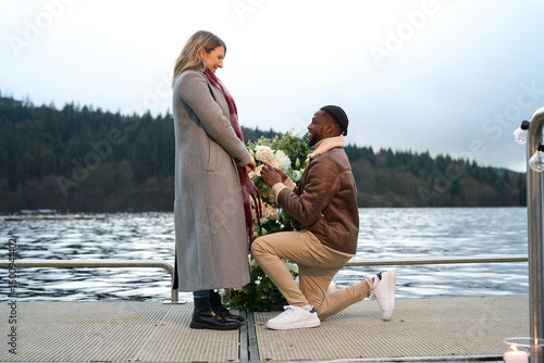 Smiling man proposing marriage to woman on bridge