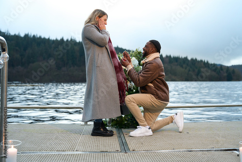 Smiling man proposing marriage to woman on bridge