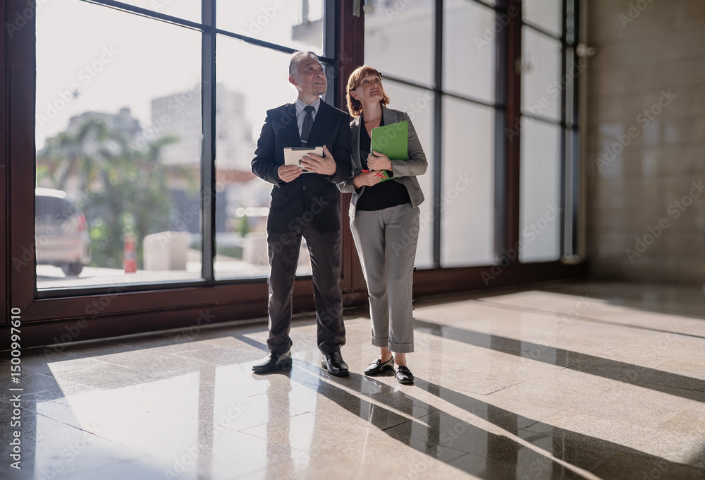 Fototapeta premium Business meeting. Mature businessman and executive woman team standing in modern office discussing corporate strategy or financial planning. Diverse people working together, successful CEO partnership