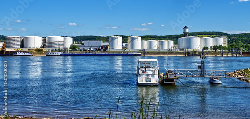 Bild auf Leinwand Large oil storage tanks at the rhine river with docked boats on a sunny day