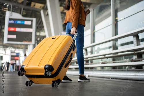 Close up of unrecognized woman tourist walking with her luggage through international airport terminal during holiday trip, female tourist rolling suitcase alone.