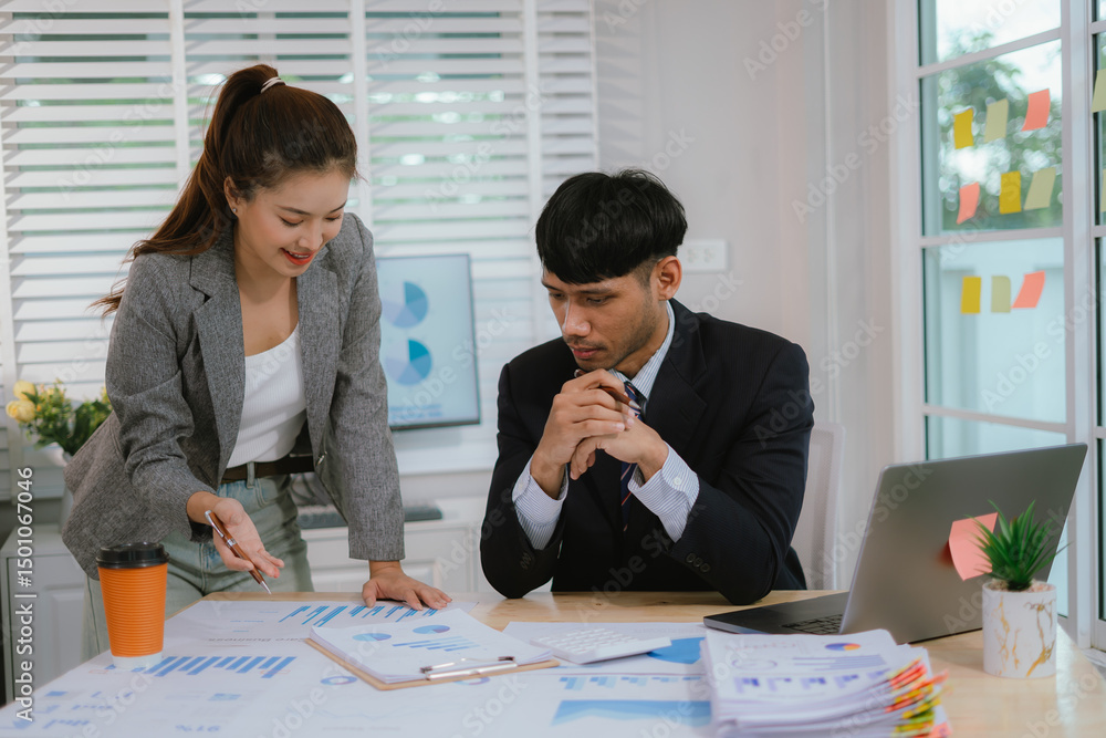 Fototapeta premium Cheerful Asian businessman and woman looking at laptop screen, analyzing project success in office.