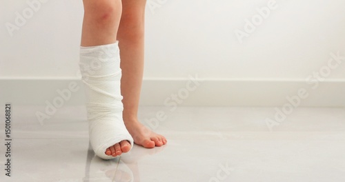 Obraz na plátně Child recovering from injury with leg in cast standing on a smooth floor in a room interior
