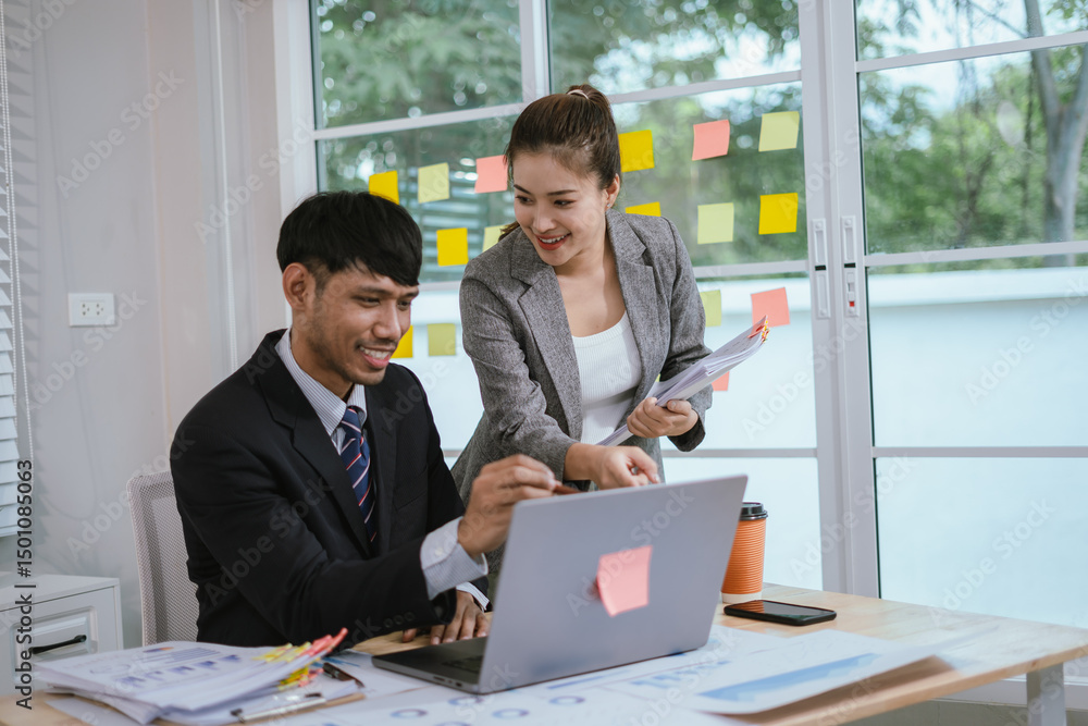 Cheerful Asian businessman and woman looking at laptop screen, analyzing project success in office. Cheerful Asian businessman and woman looking at laptop screen, analyzing project success in office.
