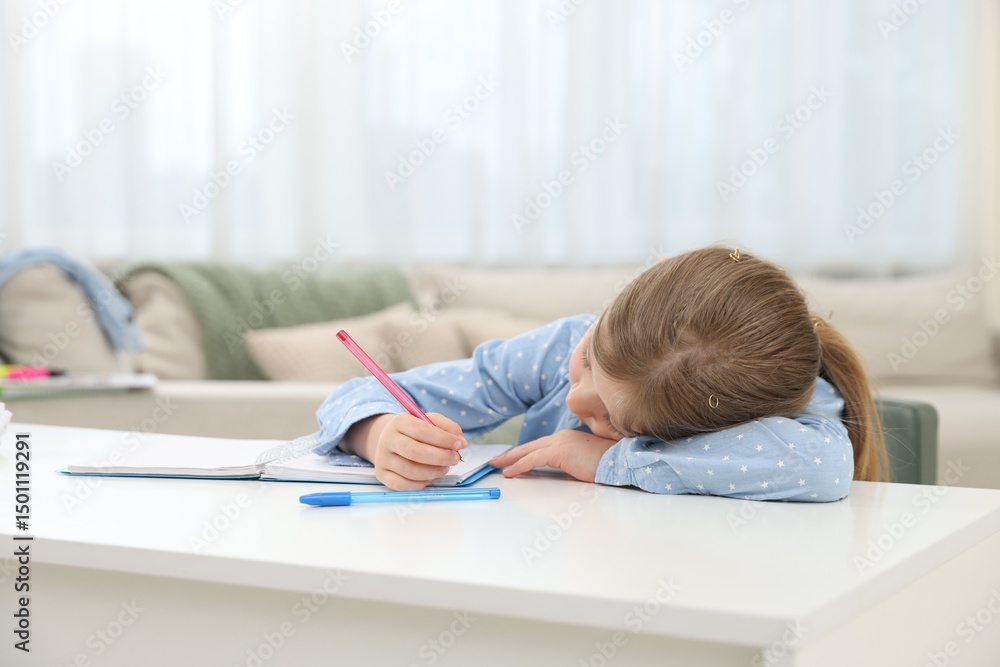 Tired little girl doing homework at table indoors Tired little girl doing homework at table indoors