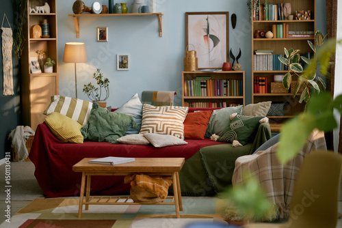 Tableau sur toile Interior of cozy living room with mix of colorful cushions, wooden bookshelves,
