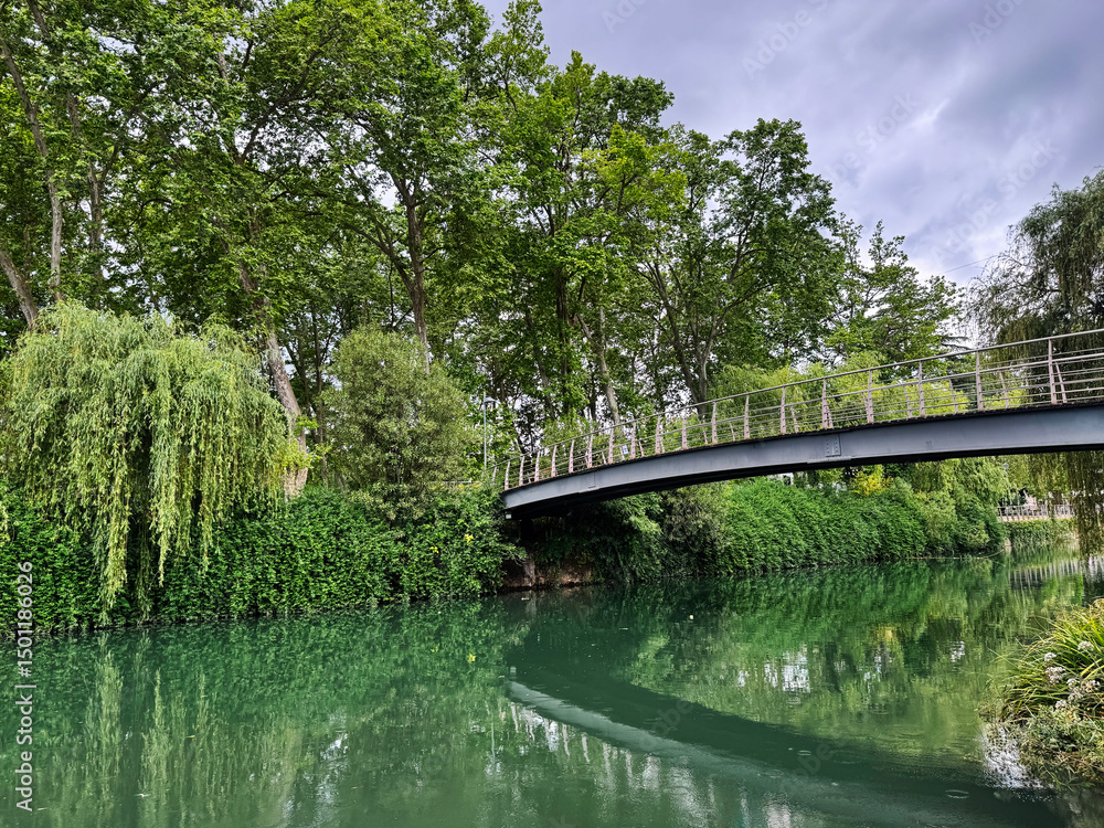 Fototapeta premium Scenic riverside view with footbridge surrounded by lush greenery