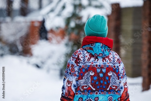 Child in colorful winter coat explores snowy streets, surrounded by serene winter landscape and frosty trees.