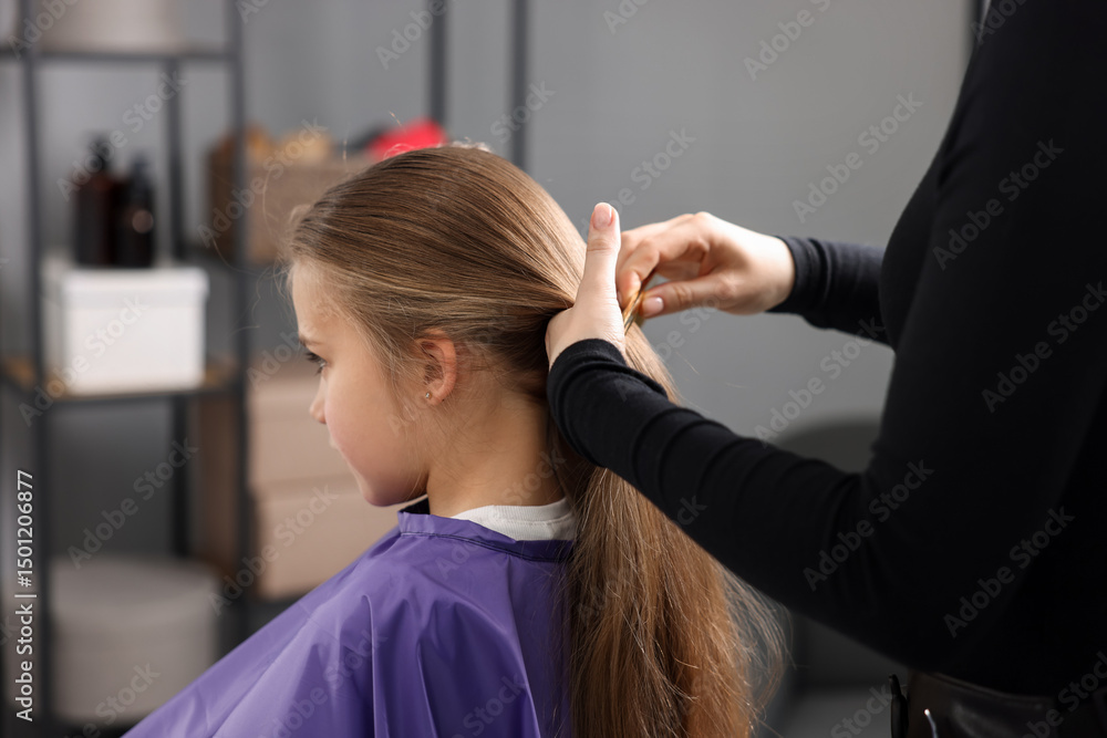 Naklejka premium Hairstylist braiding girl's hair in salon, closeup