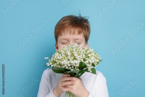 Boy with bouquet of beautiful lily-of-the-valley flowers on light blue background