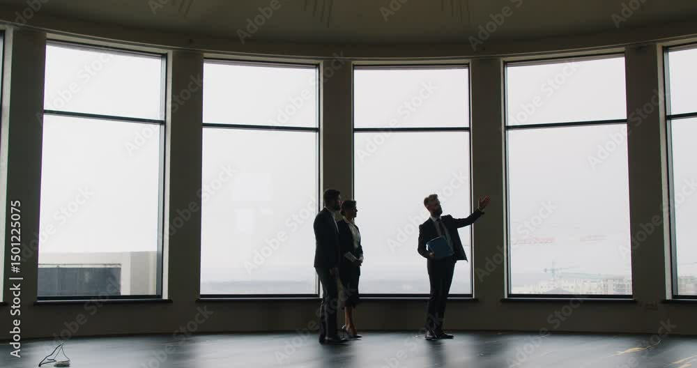 Expert realtor presenting to business professionals spacious office with large panoramic windows. Business people exploring options for purchase or rent in modern space with cityscape in background.