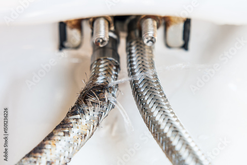 Foto The faucet connection hoses, one of which is burst and water is coming out of it under pressure