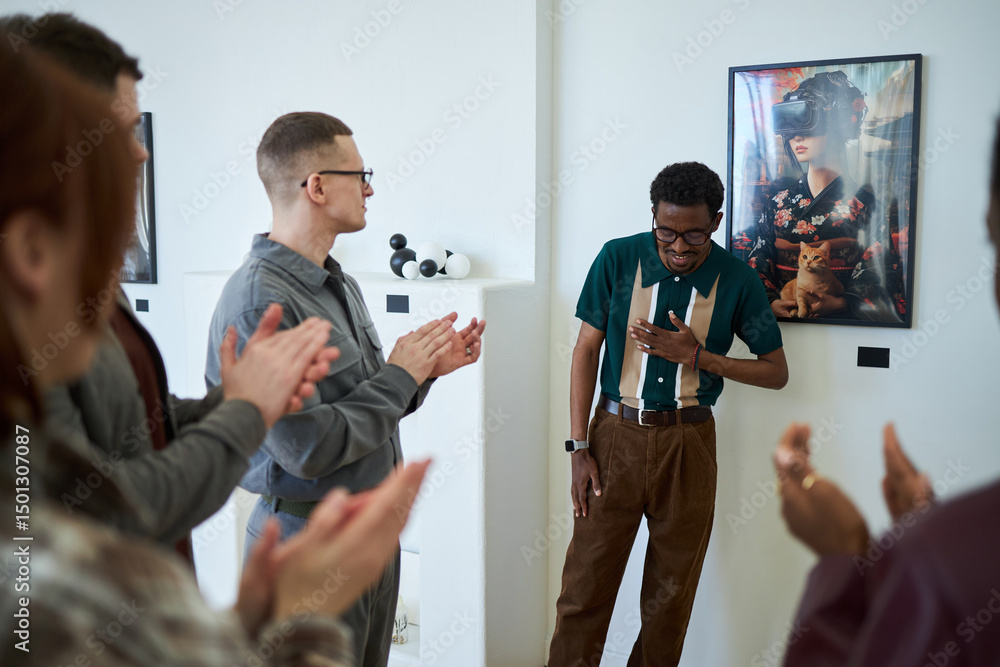 Naklejka premium Group of people applauding a man standing in modern art gallery. Man showing gratitude while surrounded by diverse individuals appreciating contemporary art installation