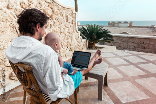 dad and his little son with a laptop are resting and working as a freelancer on vacation