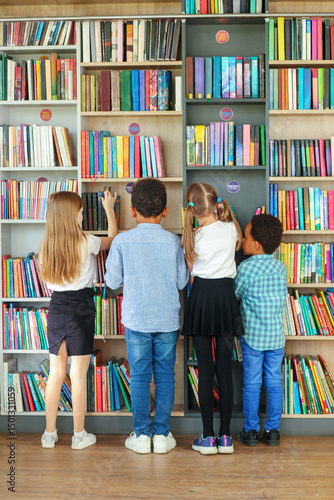 Group of children choosing books in school library.