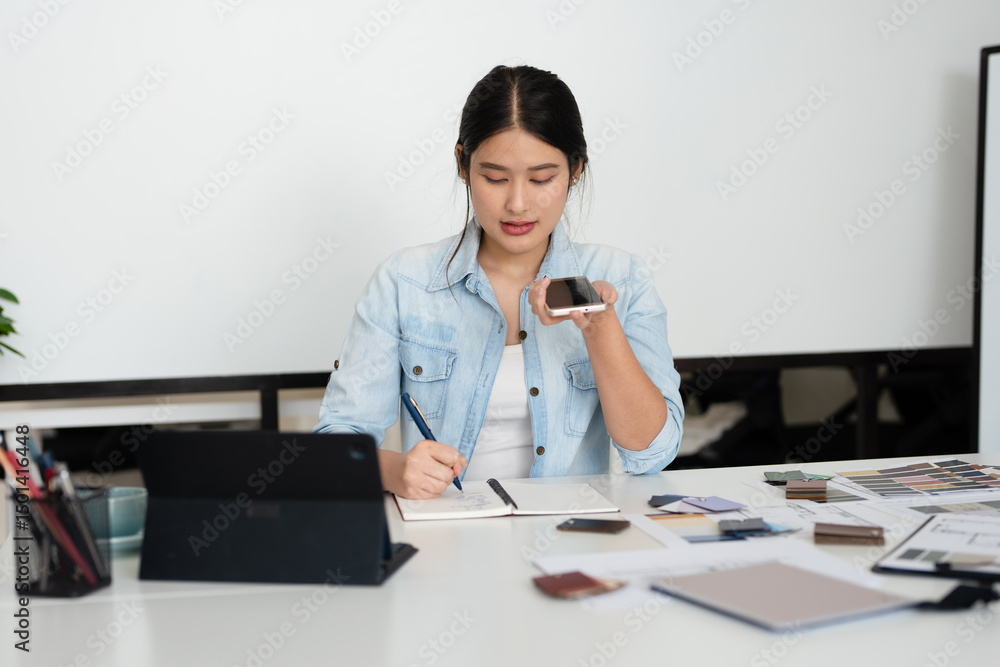 Happy interior designer speaking over the phone in her home office. Creative business woman taking notes during a phone call with her clients. Female designer working on a new project remotely. Happy interior designer speaking over the phone in her home office. Creative business woman taking notes during a phone call with her clients. Female designer working on a new project remotely.