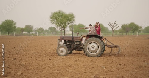 Indian village farmer young woman lady wear red saree smiling sitting on tractor outdoor Asian mother with teen age girl talk gossip old aged male man driving outside farm rural area enjoy desi life