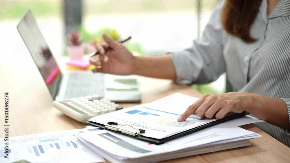 Accountant working at desk using calculator to calculate financial report in finance accounting business office concept Accountant working at desk using calculator to calculate financial report in finance accounting business office concept