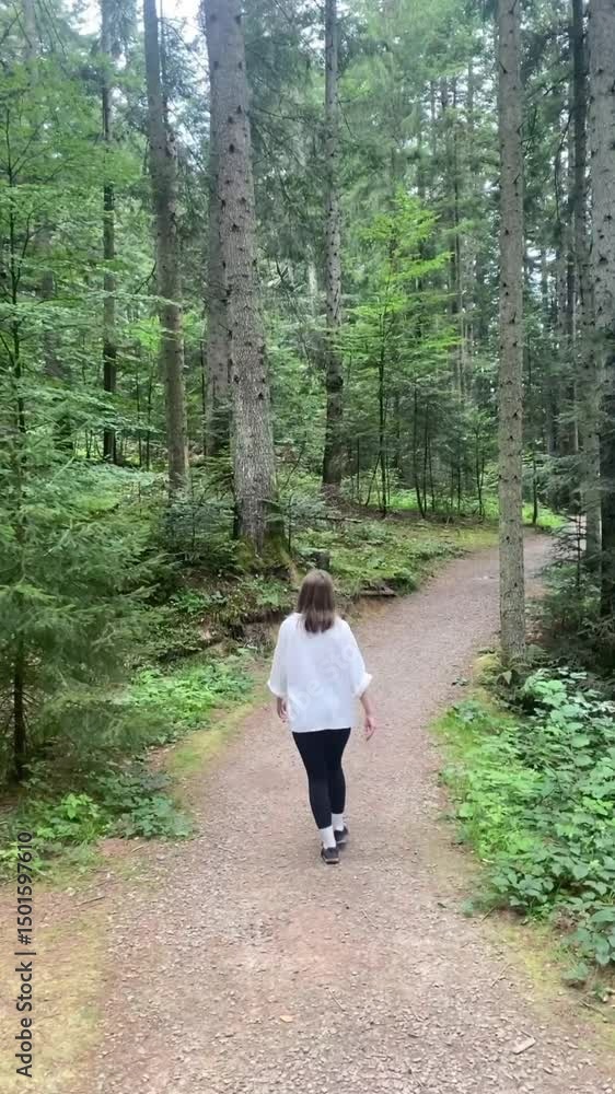 a young woman walks a path in the forest in a white shirt a young woman walks a path in the forest in a white shirt