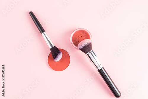 Makeup brushes with compact blush on pink background
