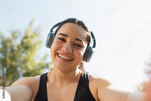 A young woman takes a selfie while listening music and practice sports in a park in the morning, Zaragoza, Spain