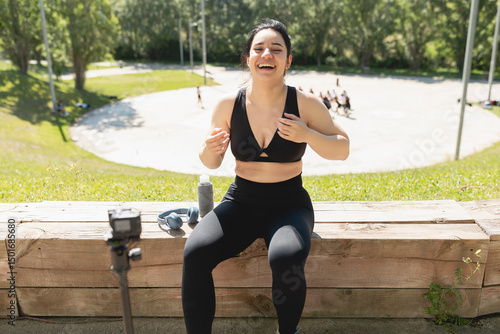 A young woman laughs happy while records herself on video, to explain to her followers, how to perform an exercise and sport workout