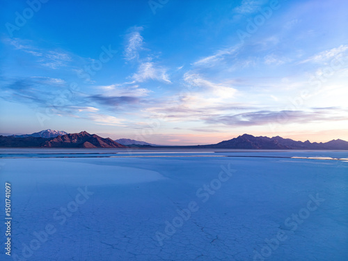Aerial view of serene bonneville salt flats at sunset with expansive sky and distant mountains, Wendover, Utah, United States.