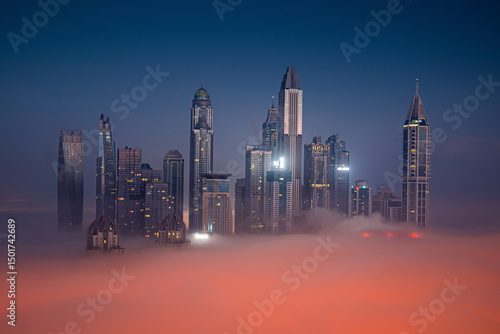 Aerial view of modern skyscrapers illuminated by city lights under a cloudy night sky, Dubai Marina, Dubai, United Arab Emirates.