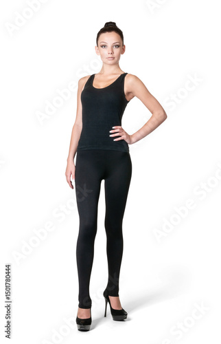 A young, confident woman in a black tank top and leggings stands with her hand on her waist, isolated on a transparent background PNG.