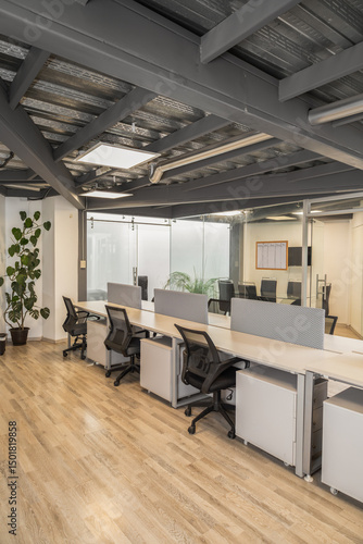 A bright office space featuring multiple modern cubicles where employees work diligently, highlighting productivity and organized workspace design.

