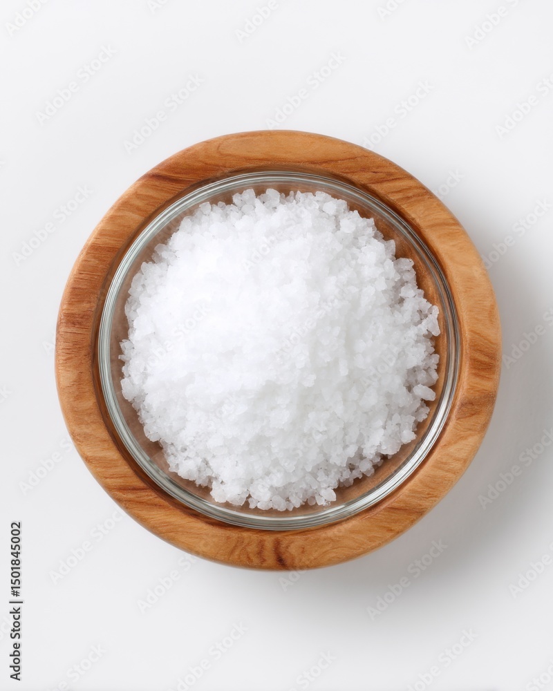 Overhead shot of sea salt crystals in a glass bowl with wooden base on white background for cooking and seasoning Overhead shot of sea salt crystals in a glass bowl with wooden base on white background for cooking and seasoning